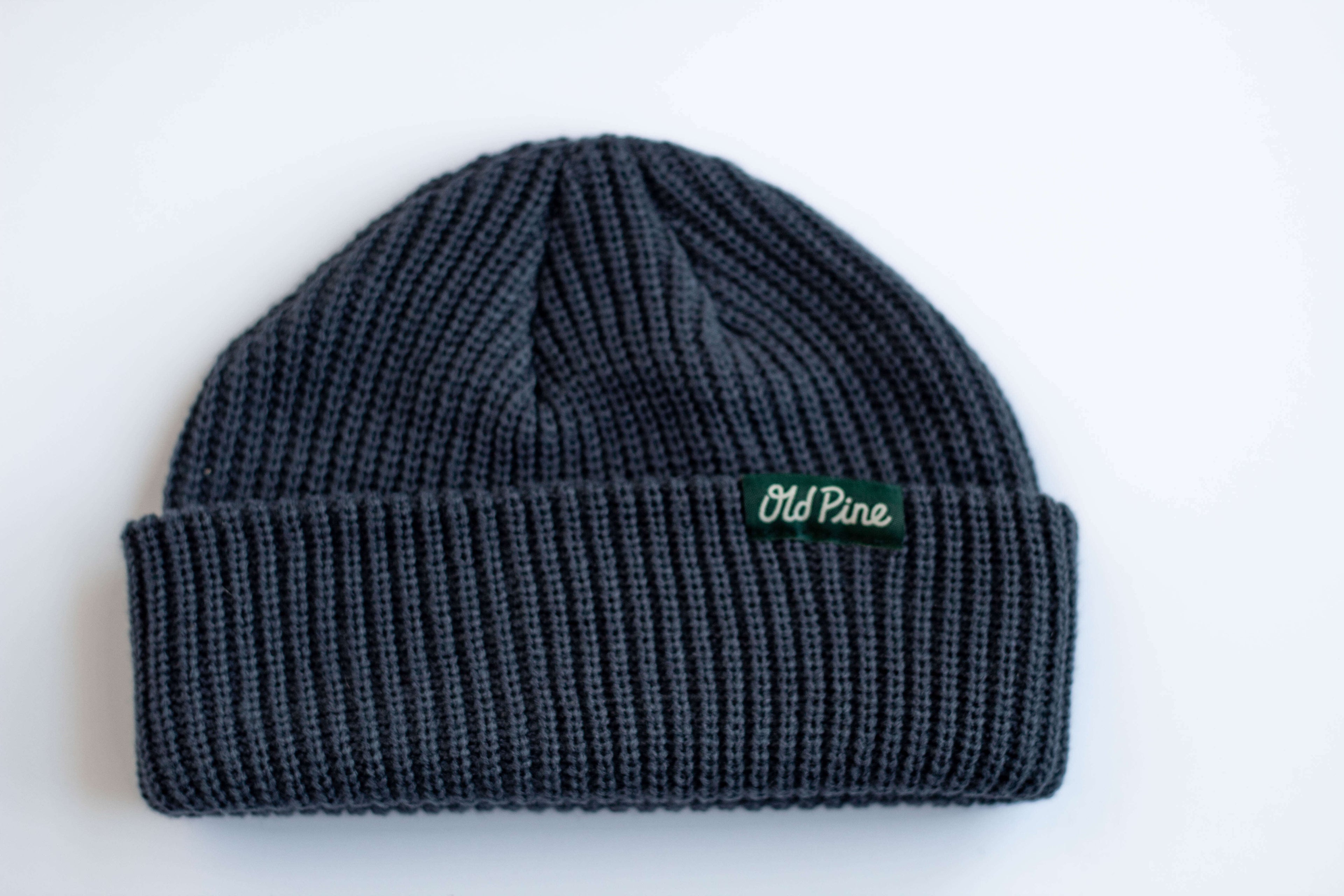 Blue beanie with a green "old pine" label on a white background