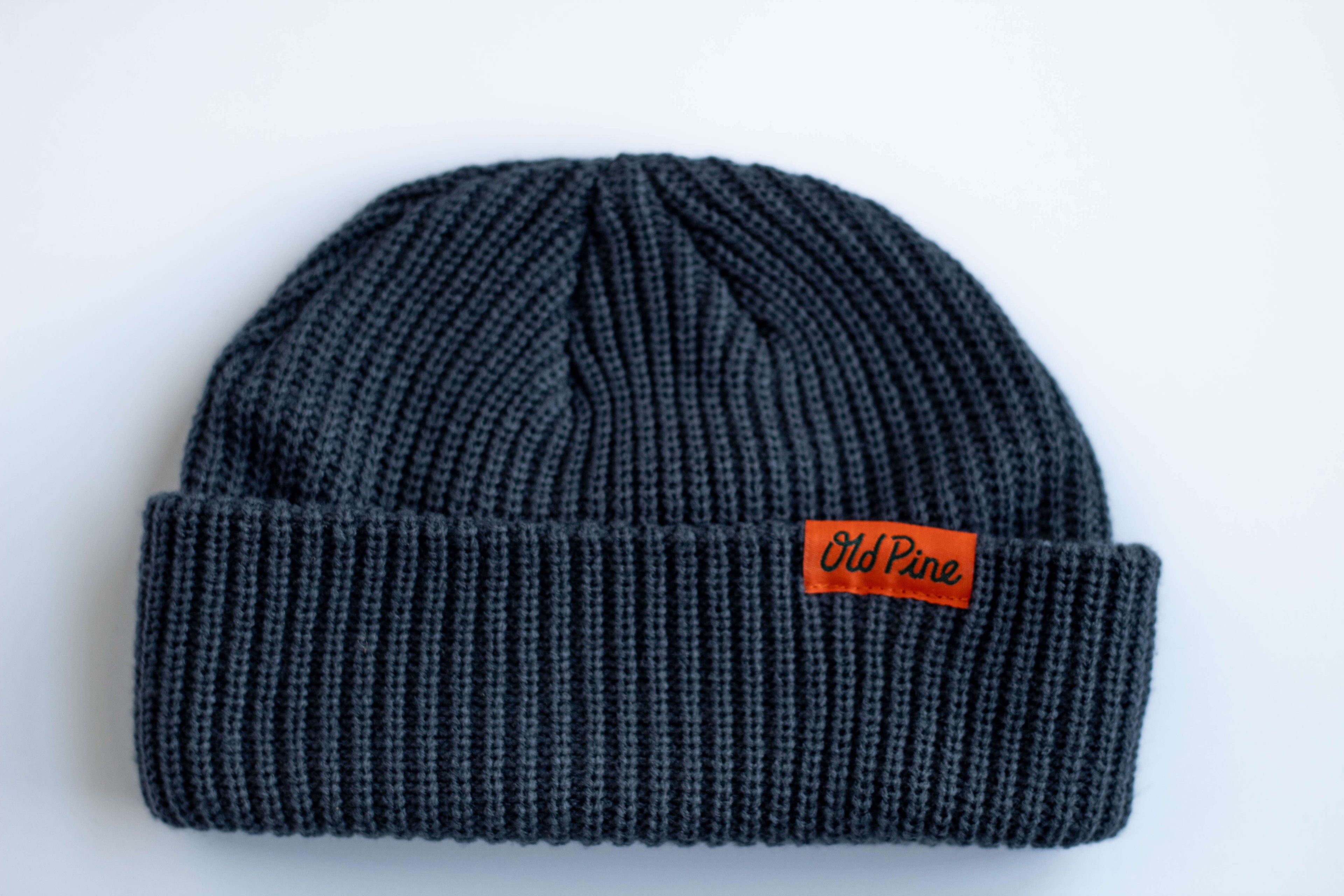 Blue beanie with an orange "old pine" label on a white background