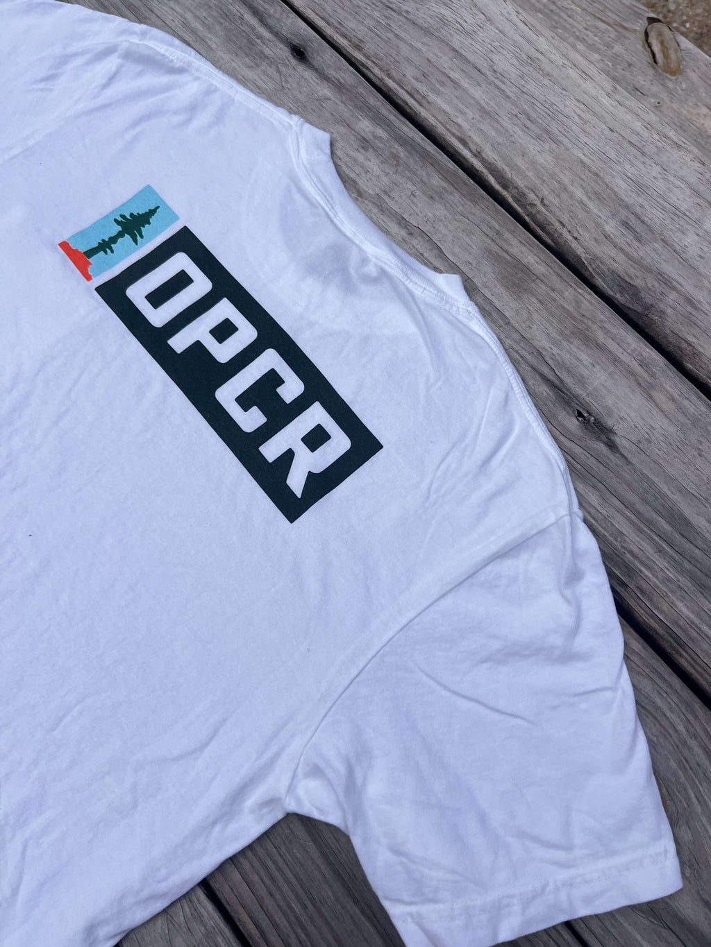 Backside of a white t-shirt with an OPCR logo and text